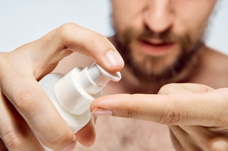 man applying beard oil on fingers