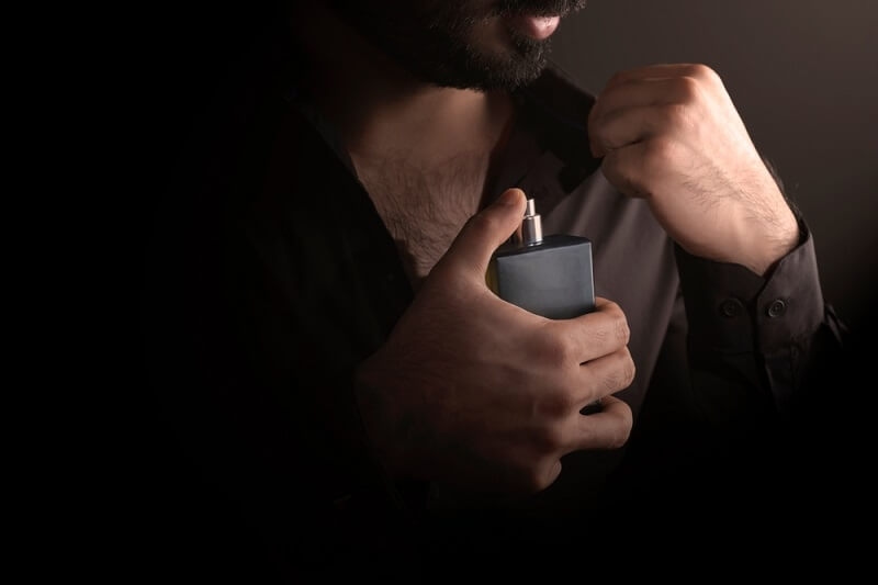 man applying perfume in collarbone
