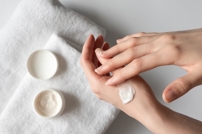 girl taking moisturizer on hand before applying on face as a skincare routine