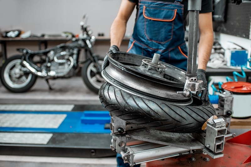 Service worker changing motorcycle tire on a special equipment for tire installation in the workshop for motorcycle repairment