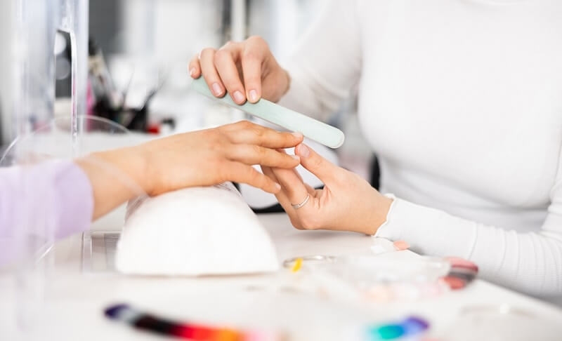 woman in manicure session getting her nail grit with file