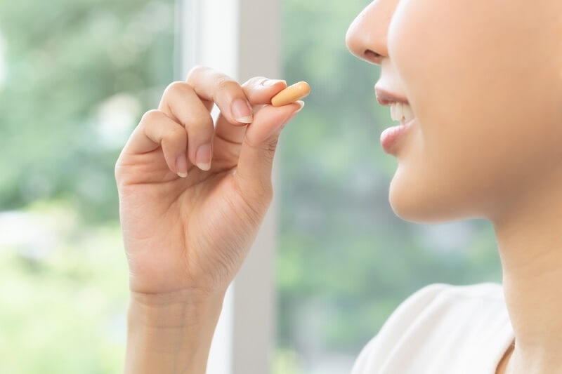 woman eating multivitamins for nail health