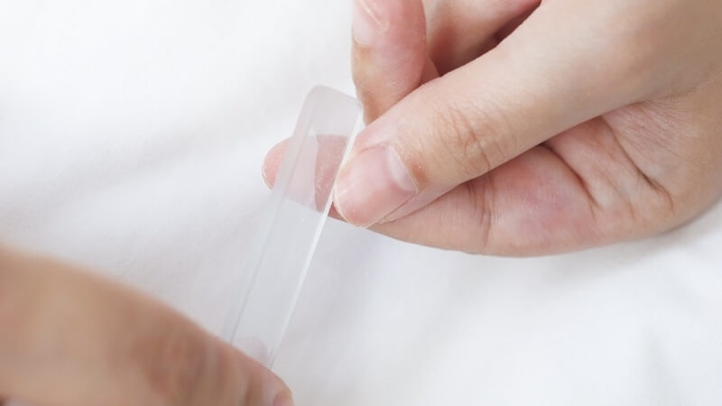 woman cleaning her nails and removing extra with filers