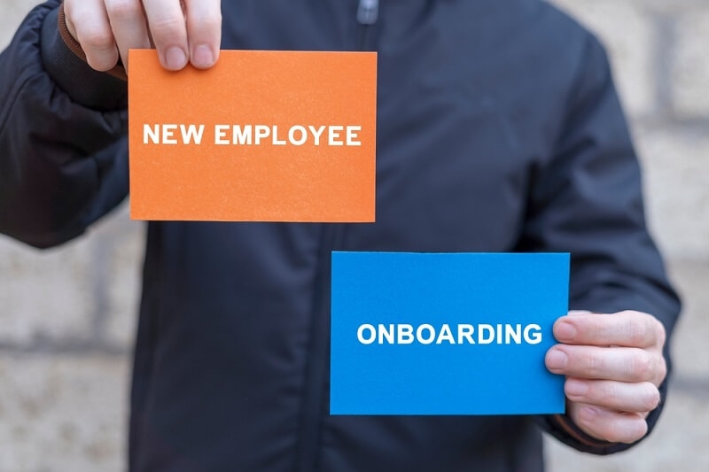 employee holding new employee and onboarding text slip in hand