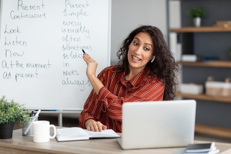 woman tutor explaining concepts written on board to students virtually