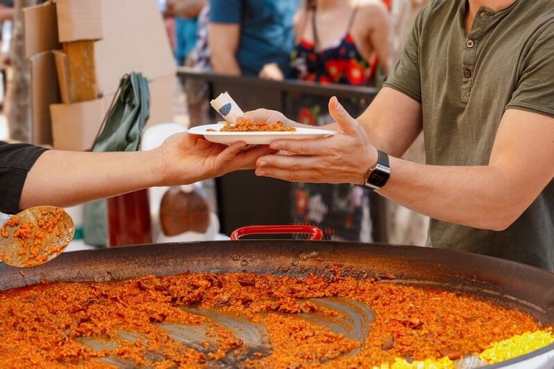man taking paella from chef in paella festival