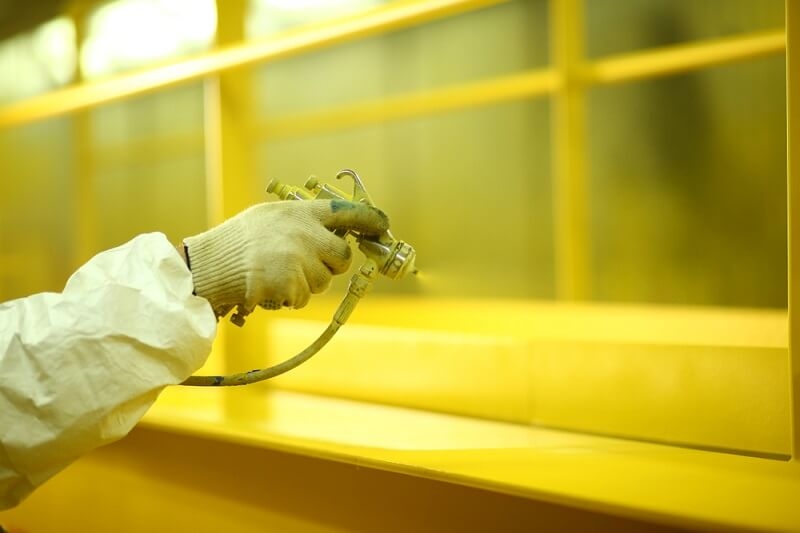 worker spraying thin paints on surface