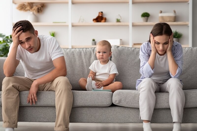 couple feeling mentally stressed while sitting on couch with kid