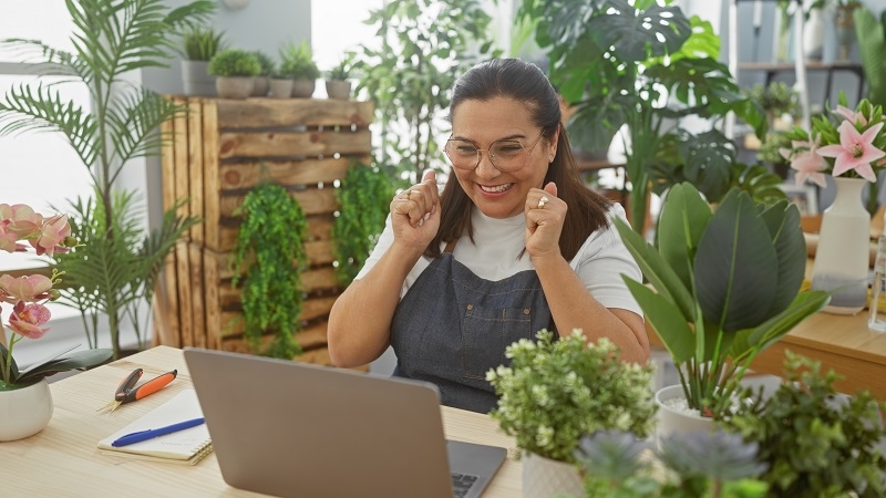 Smiling hispanic woman enjoying success in a flower shop