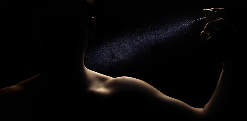 man applying perfume from a distance