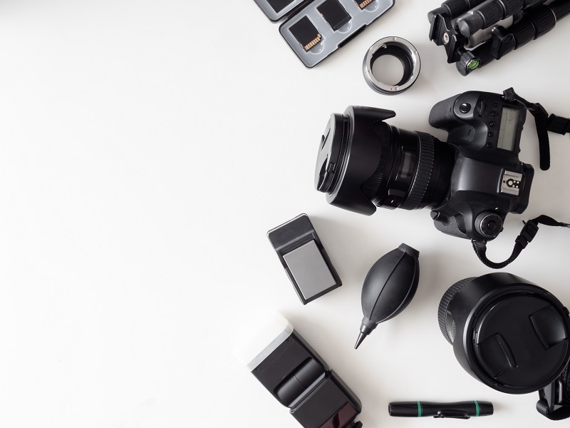top view of work space photographer with digital camera, flash, cleaning kit, memory card, tripod and camera accessory on white table background