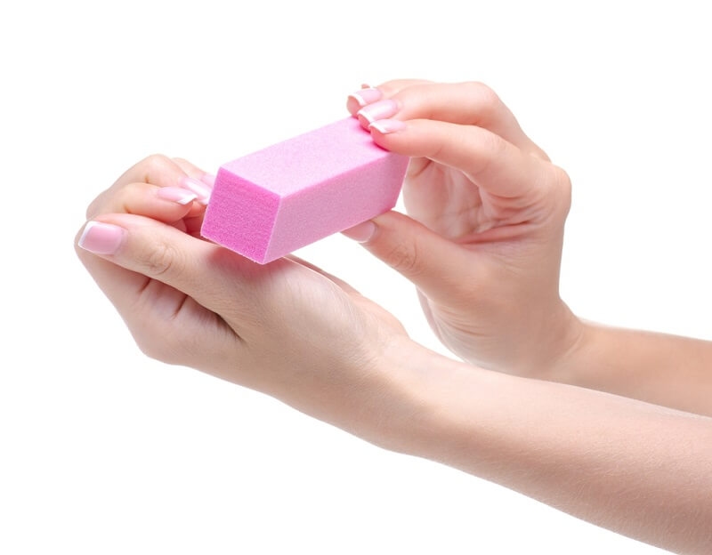woman cleaning nails with nail buffer after manicure