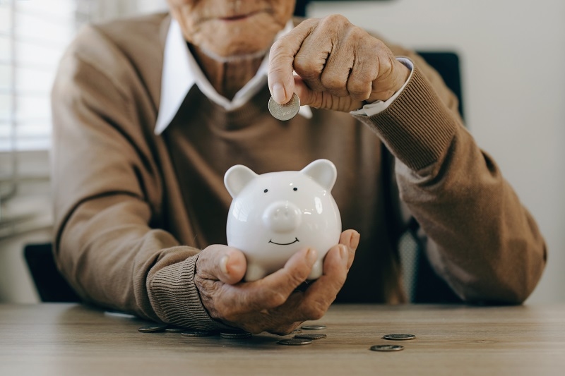 Saving money investment for future. old man hand putting money coins