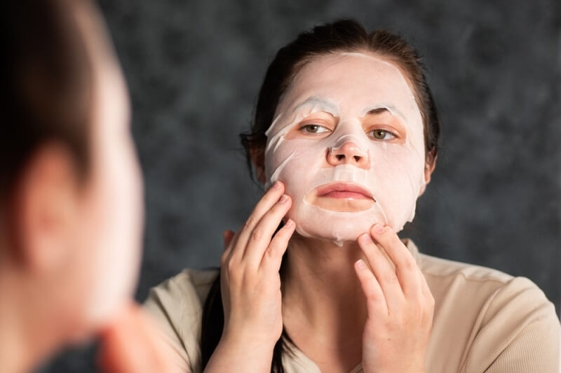 woman following combination skin routine while applying face mask