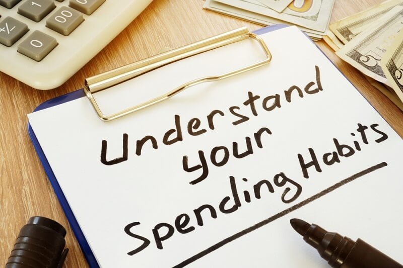 man writing spending habits on notes with calculator