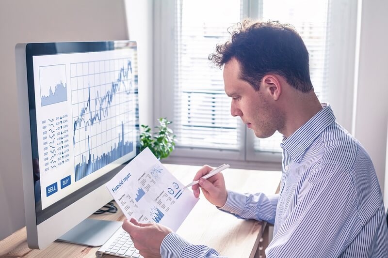trader analyzing stocks by comparing financial report