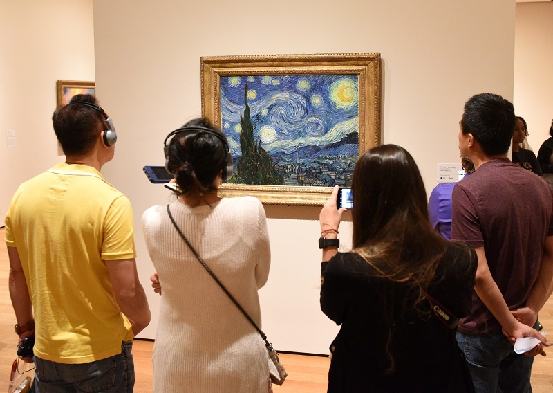 People near the Starry Night by Vincent van Gogh painting in Museum of Modern Art in New York City.