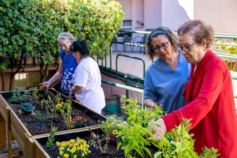 old woman and caregivers looking therapeutic plants