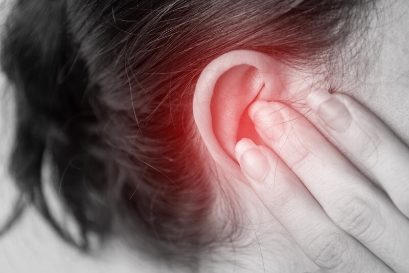 woman feeling pain in ear and holding it