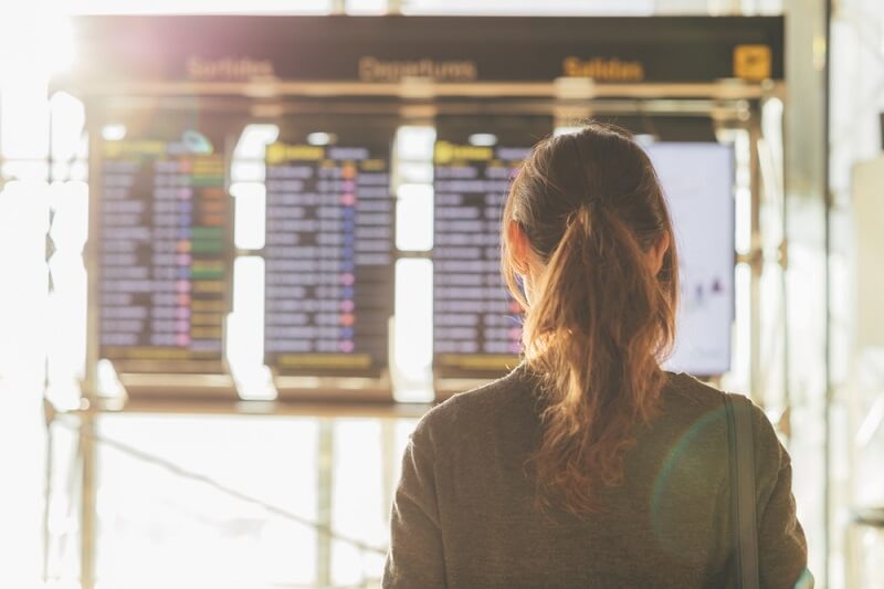 woman looking at digital board in airport for status