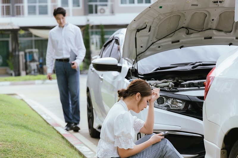 woman inspect a damaged car after an auto accident. The insurance agent examines the vehicle