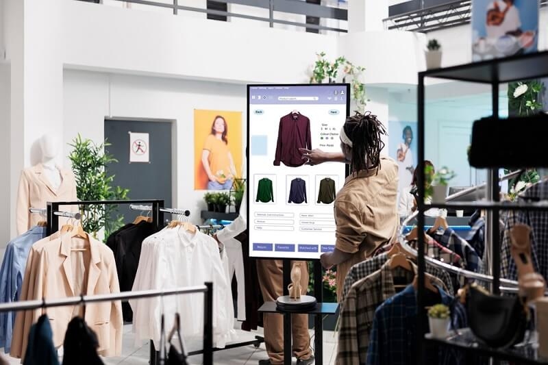 man showing virtual clothing screen in showroom
