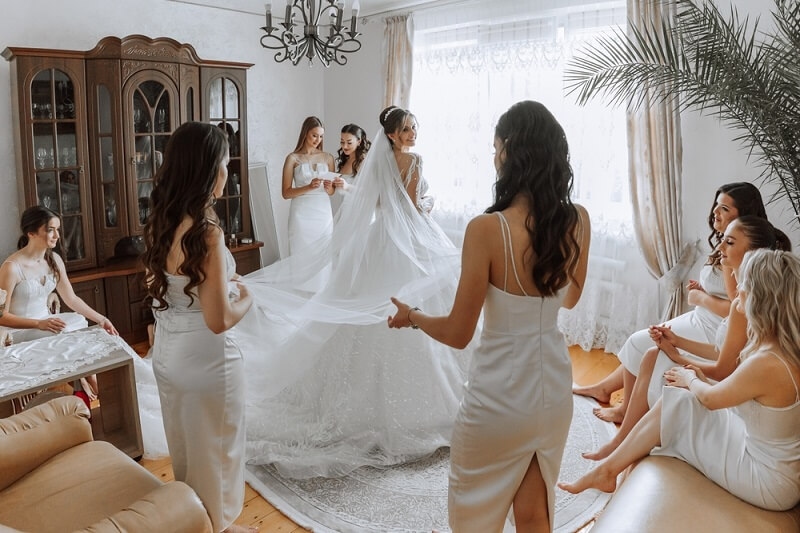 bridesmaid checking bride wedding dress