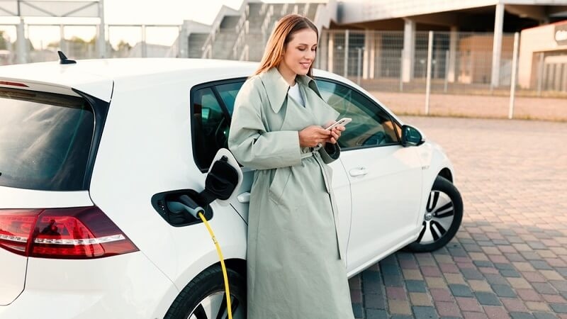 woman scrolling phone until car charges