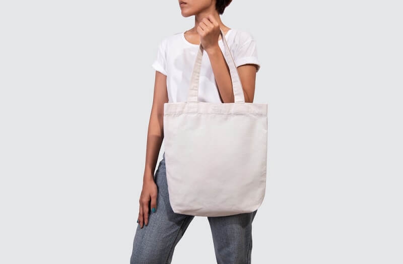 woman carrying white canvas handbag