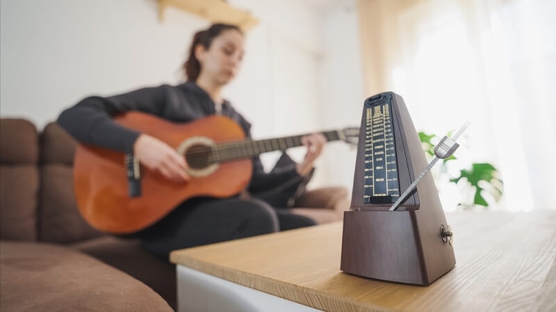 woman guitarist practicing with vibrating metromone