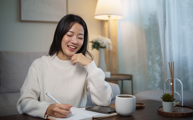 woman smiling and writing journal in free time
