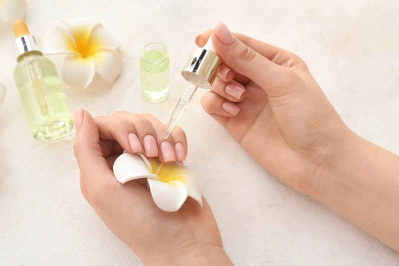 woman applying cuticle oil on her nails