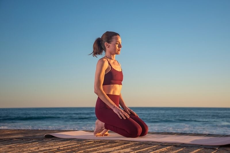woman doing yoga on matt near by ocean