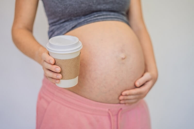pregnant woman holding coffee cup