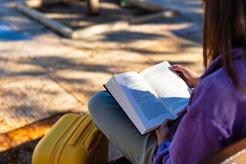 woman reading novel while travelling