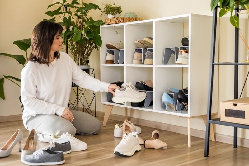 woman arranging shoe in wooden shoe rack