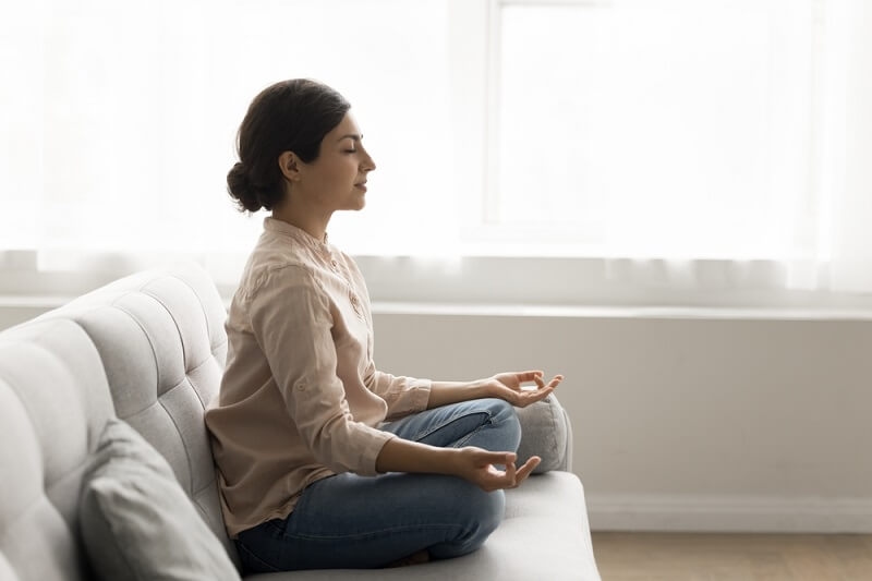 woman sitting on couch and doing meditation