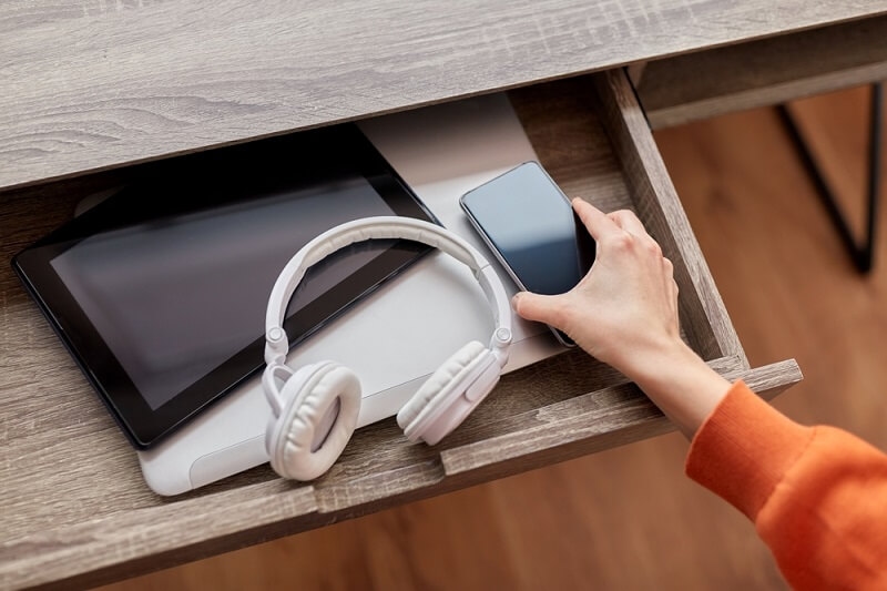 woman keeping smartphone in drawer