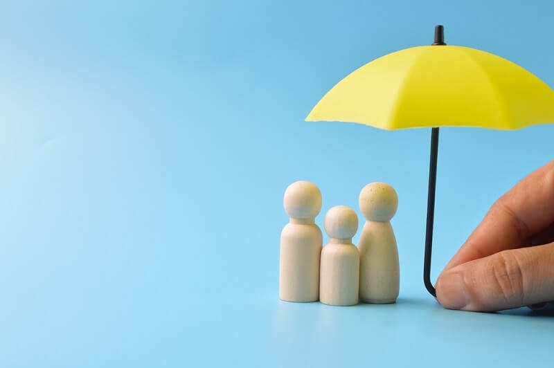 man showing yellow umbrella covering three wooden blocks