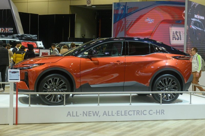 Orange 2026 Toyota C-HR all-electric SUV displayed at an auto show.