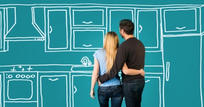 Happy embracing couple planning their home kitchen furnishing renovation. Sketch kitchen drawing.
