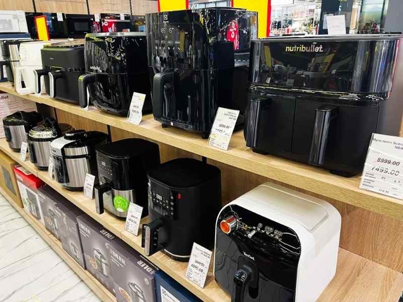 Display shelf filled with various air fryer models in an electronics or appliance store.