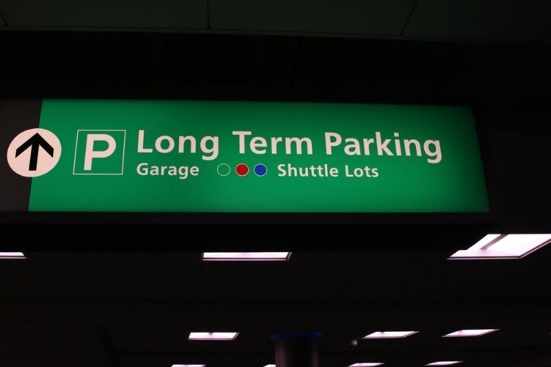 Airport long-term parking sign directing travelers to parking garage and shuttle lots.