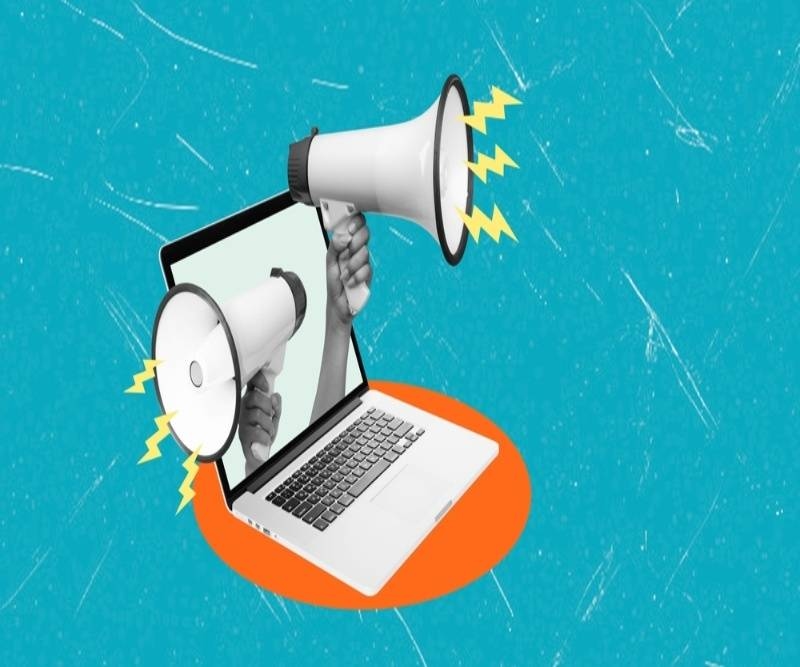 Hands hold megaphones on either side of a laptop screen, symbolizing the power of digital media in amplifying communication.