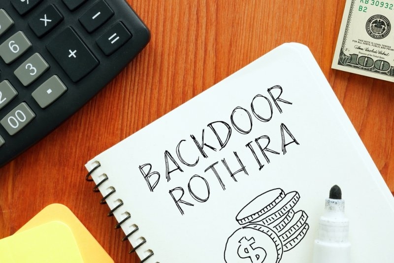 Text  Backdoor Roth IRA on a notepad with calculator and dollars on side