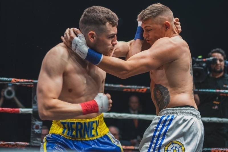 Close-range boxing action as two fighters grapple and exchange blows during a competitive bout.