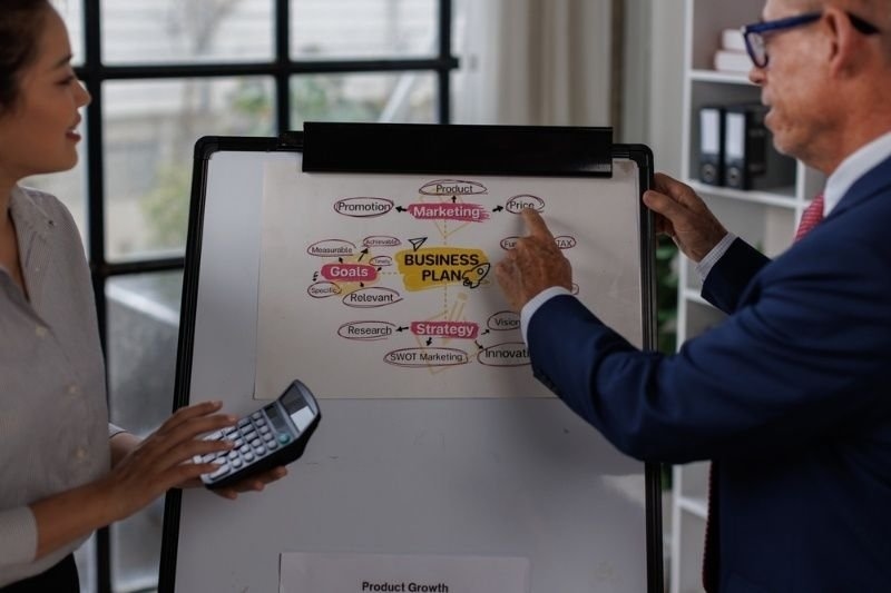 Business professionals discussing a business plan on a presentation board during a meeting in an office.