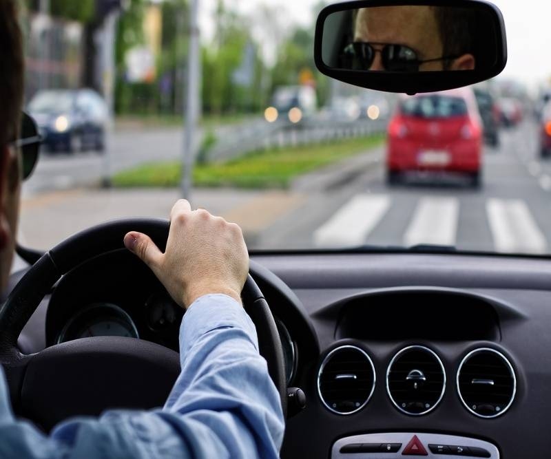 Close up look of a man driving car, hands on steering wheel.