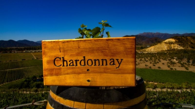 Text Chardonnay on a wooden plate kept on top of a barrel