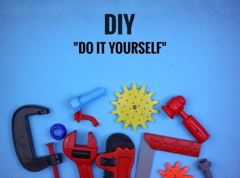 DIY ‘Do It Yourself’ concept image with colorful toy tools and hardware items on a blue background.